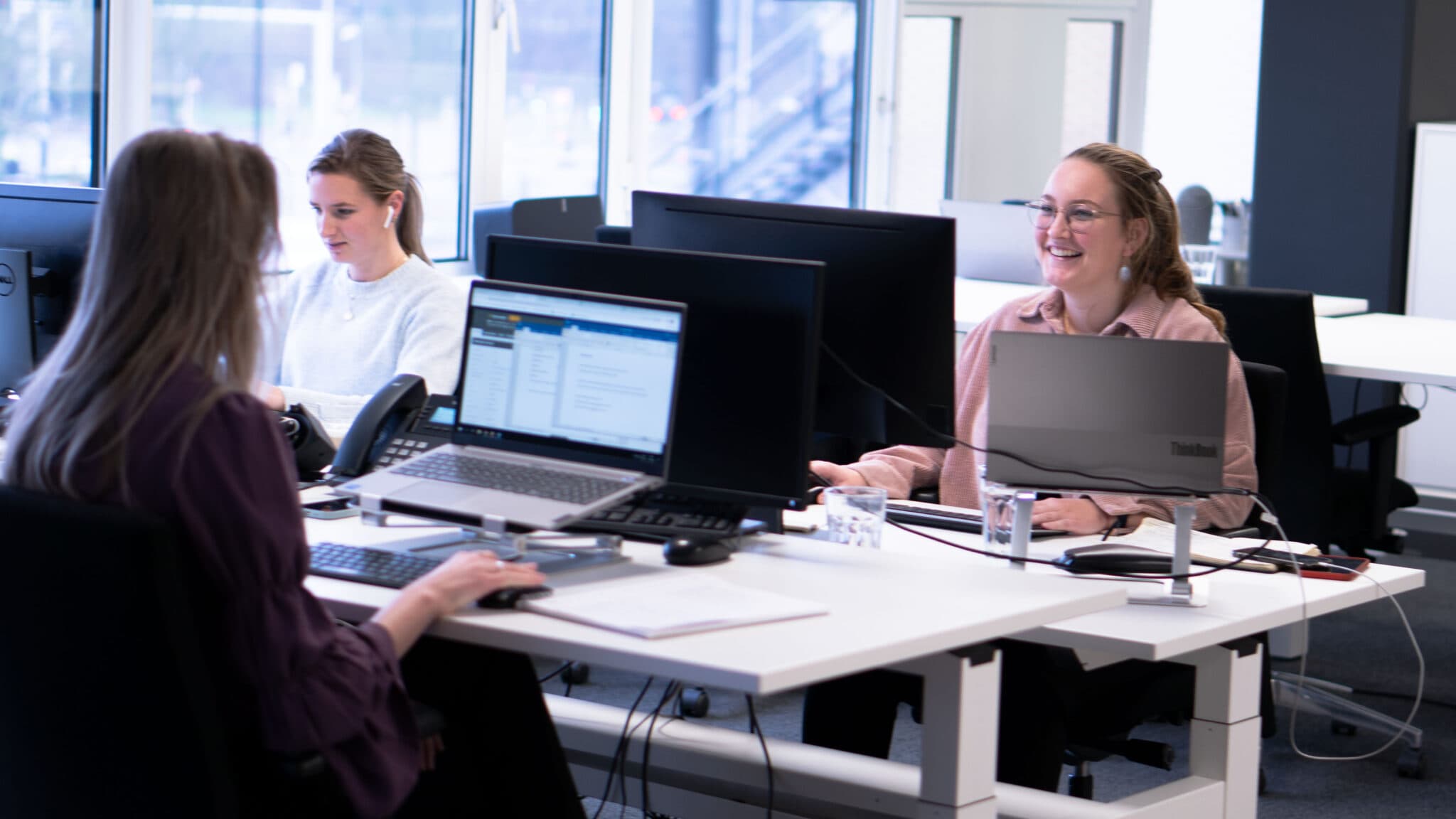 Drie talentcoaches geconcentreerd aan het werk achter hun computers bezig met het ontwikkelen en ondersteunen van talenten in een kantooromgeving