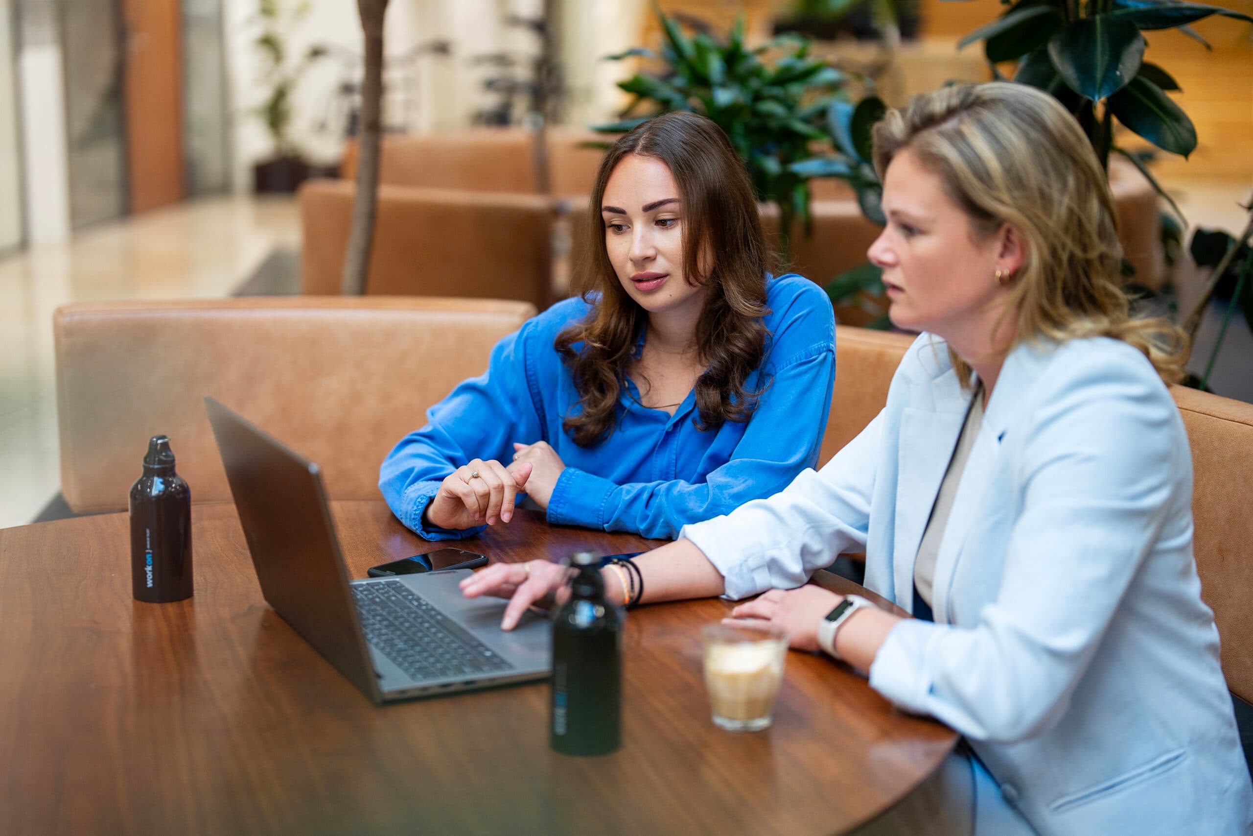 Blije vrouw achter haar laptop aan bureau is zich aan het inschrijven bij Work-on terwijl zonlicht de kamer binnenschijnt